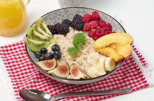 avena hervida con fruta en un plato redondo sobre una mesa blanca, desayuno saludable. vista desde arriba foto