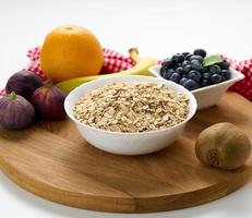 avena cruda en plato de cerámica blanca y frutas en mesa blanca, desayuno foto