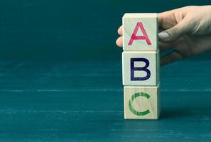 la mano sostiene cubos de madera con letras a, b, c. concepto de educación preescolar. verdades simples y una lista de logros y metas foto