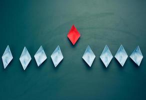 group of paper boats on a green background. concept of a strong leader in a team photo