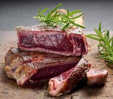 trozo frito de chuletón de ternera, cortado en trozos sobre una tabla de madera marrón, cocción rara foto