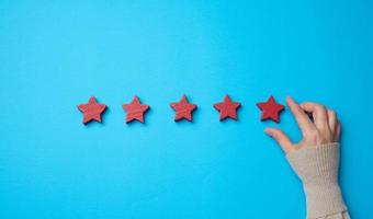 Five red stars and a hand on a blue background. Evaluation of the quality of services photo