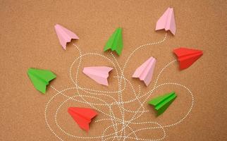 group of multicolored paper planes with long tangled paths on a brown background. photo
