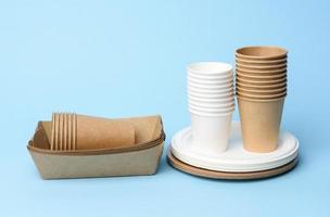 stack of white and brown paper cups and round plates on a blue background photo