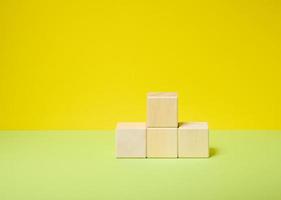 wooden cubes stacked in a pedestal on a yellow-green background, a place to display any product cosmetics, food, drinks photo