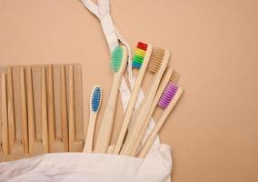 white cotton bag, wooden toothbrushes on a brown background. Recyclable waste, top view photo