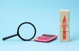 magnifier and calculator on a blue background. Income and expense growth concept photo