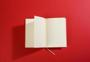 open notebook with blank white sheets on red background photo