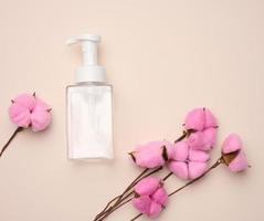 empty plastic container with dispenser for liquid products, soap or shampoo on beige background photo