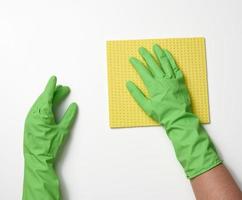 dos manos femeninas con guantes protectores de goma para limpiar sostienen un estanque amarillo sobre un fondo blanco foto