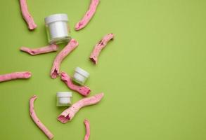 empty white jar for cosmetics on a green background. Packaging for cream, gel, serum, advertising and product promotion. Mock up, top view photo