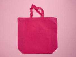 empty viscose eco friendlypink canvas tote bag for branding on a pink background. Clear reusable bag for groceries, mock up photo