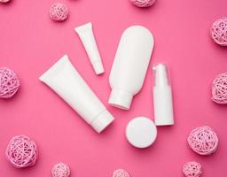 frasco, botella y tubos de plástico blancos vacíos para cosméticos sobre un fondo rosa. embalaje para crema, gel, suero, publicidad y promoción de productos, maqueta foto