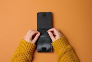 two female hands hold black leather open empty wallet for cash, top view photo