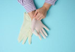 process of putting white latex gloves on hand on blue background, hygiene protector photo
