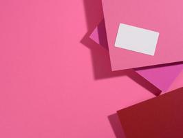 blank rectangular business card lies on a modern pink background sheets of paper with a shadow photo