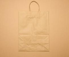 large disposable brown kraft paper bag with handles on a brown background, eco packaging, zero waste photo