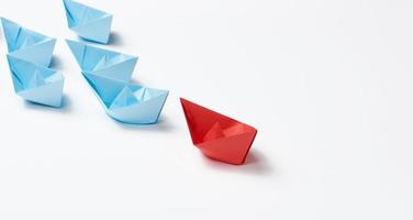 group of paper boats on a white background. concept of a strong leader in a team, manipulation of the masses, following new perspectives, collaboration and unification. Startup photo