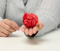 female hand holds a crumpled red ball of paper. photo