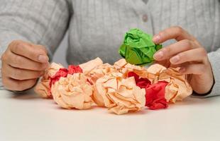 la mano femenina sostiene una bola de papel verde arrugada. Idea Nueva foto