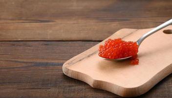 red caviar of pink salmon lies in a wooden spoon photo