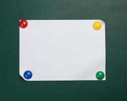 blank white sheet of a4 paper hanging on a green magnetic board. photo