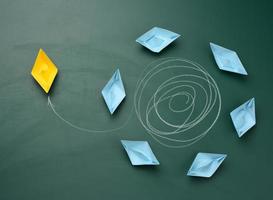 group of blue boats is floating in a circle, one yellow one has escaped from the trajectory and is sailing in the other direction. photo