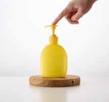 dispensador de recipientes de plástico amarillo sobre un fondo blanco. recipiente para jabón líquido, champú foto
