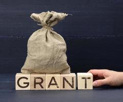 brown bag full and wooden cubes with the inscription grant. Help and gifting concept, help for beginners in business photo