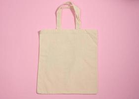 bolsa de lona beige ecológica de lino vacía para la marca sobre un fondo rosa. bolsa transparente reutilizable para comestibles, maqueta. endecha plana foto
