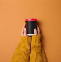 la mano sostiene una taza marrón de cartón de papel para café. vajilla ecologica foto