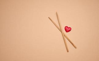 two wooden chopsticks on a brown background, copy space photo