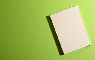 closed notepad on green background with shadow, top view photo