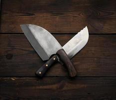 metal sharp kitchen knives in a wooden handle on a brown table made of boards, top view photo