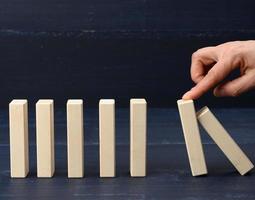 finger stops the fall of wooden bars on a blue background photo