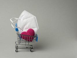 disposable medical mask in a miniature trolley on a gray background photo