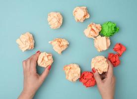 hand hold crumpled sheets of colored paper on a blue background. Solution concept, brainstorming photo