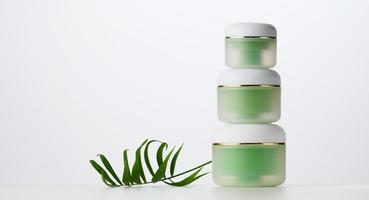 green jar for cosmetics on a white table. Packaging for cream, gel, serum, advertising and product promotion photo