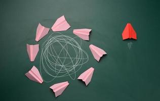 group of pink planes fly in a circle with an intricate trajectory and one flies in a straight path. The concept of thinking outside the box, uniqueness. photo