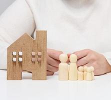 casa de madera y figuras de una familia. concepto de seguro inmobiliario, familia feliz foto