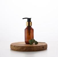 Brown glass bottle with black pump of cosmetic products on white table. Natural organic spa cosmetic, beauty concept photo
