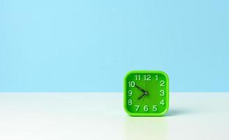 square green clock with white numbers on a white table, ten minutes to eight in the morning photo