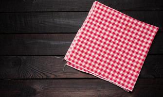 folded red and white cotton kitchen napkin on a wooden brown background, top view, copy space photo