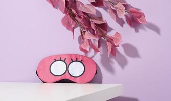 pink textile sleep mask on white table photo