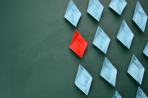 group of paper boats on a green background. concept of a strong leader in a team, manipulation of the masses, following new perspectives, collaboration and unification photo