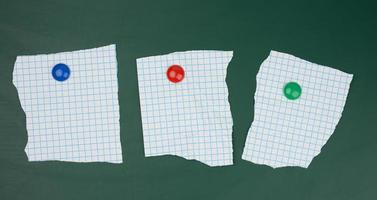 blank sheets of paper in a cage attached to a green magnetic board photo