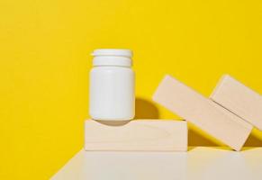 white plastic jar for pills, cream and medicines on a yellow background. Container for substances photo