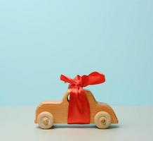 coche de juguete de madera para niños con un lazo rojo sobre un fondo azul foto