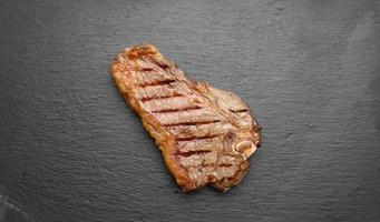 whole fried New York beef steak on a black board, striploin doneness rare photo