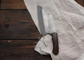 metal sharp kitchen knife in a wooden handle on a brown table made of boards photo